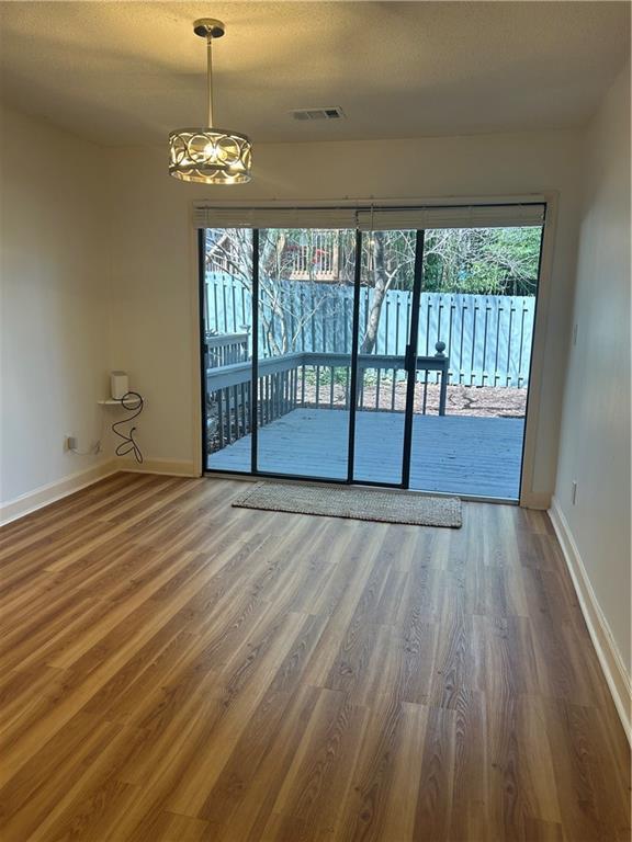 spare room with visible vents, wood finished floors, baseboards, and a textured ceiling