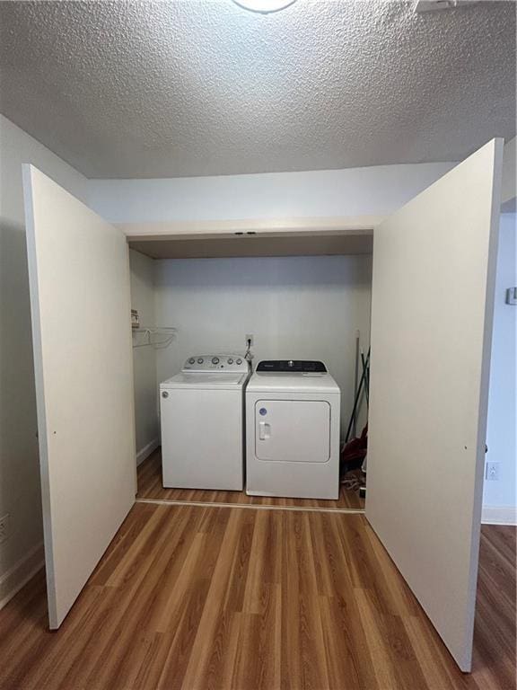 washroom with washing machine and clothes dryer, a textured ceiling, and wood finished floors