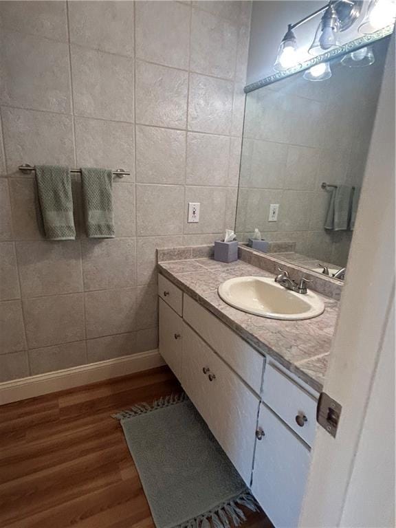 bathroom with vanity, tile walls, wood finished floors, and baseboards