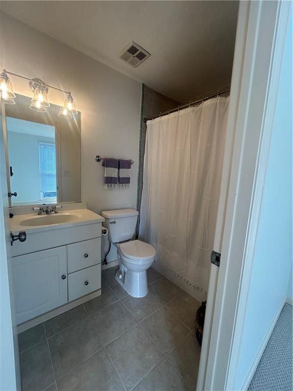 bathroom with vanity, a shower with curtain, visible vents, tile patterned flooring, and toilet