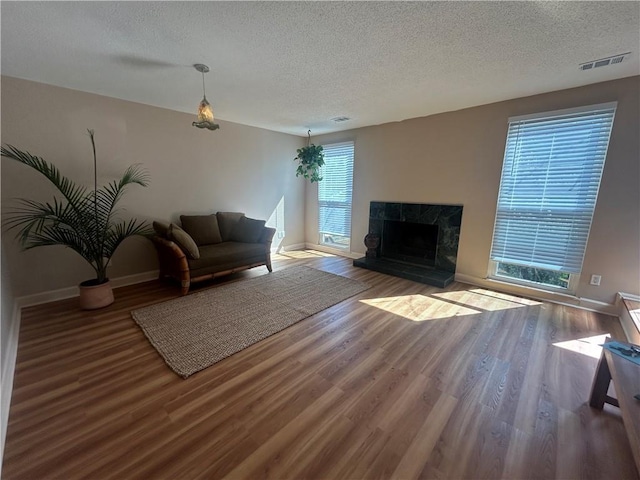 living area with visible vents, a tile fireplace, a textured ceiling, and wood finished floors