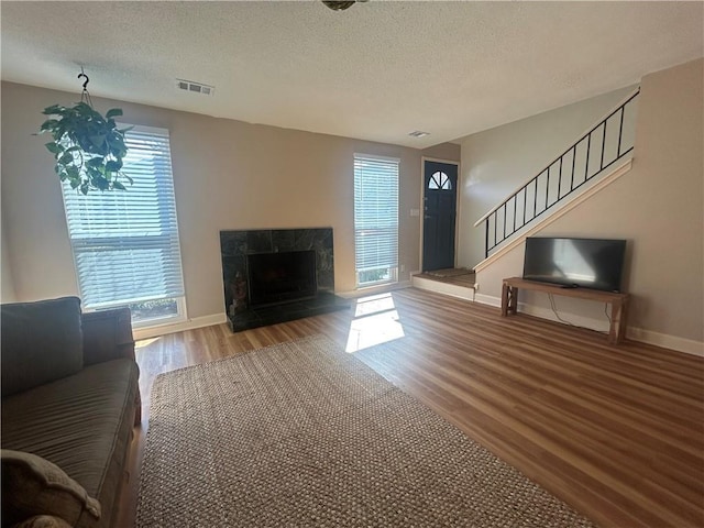 unfurnished living room with a high end fireplace, visible vents, stairs, and wood finished floors