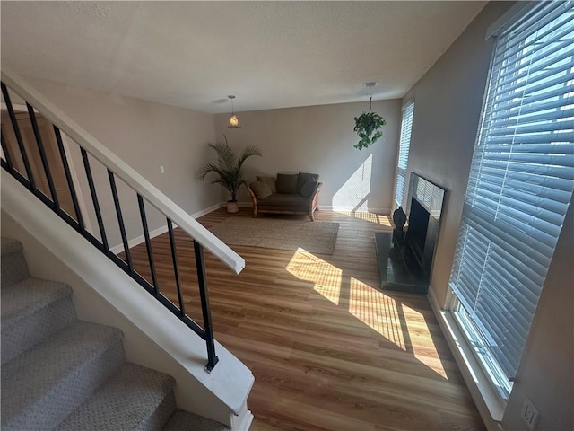 stairs with a fireplace with raised hearth, baseboards, and wood finished floors