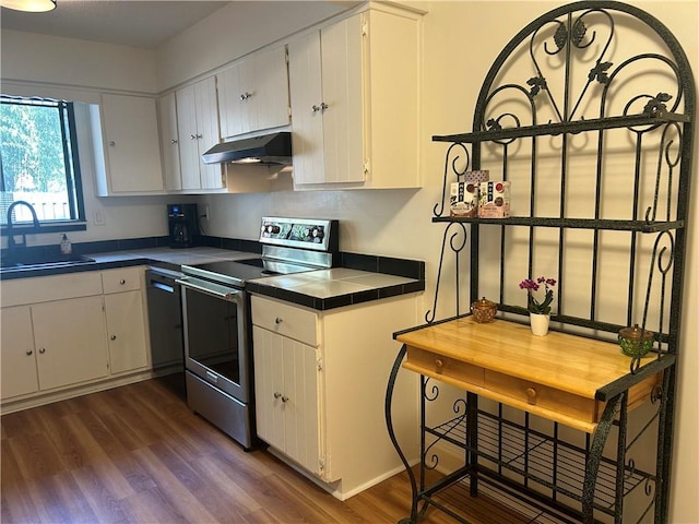 kitchen with stainless steel electric range oven, a sink, tile counters, dark wood-type flooring, and under cabinet range hood