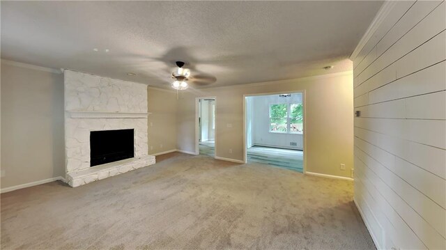 unfurnished living room with a fireplace, carpet, crown molding, ceiling fan, and wooden walls