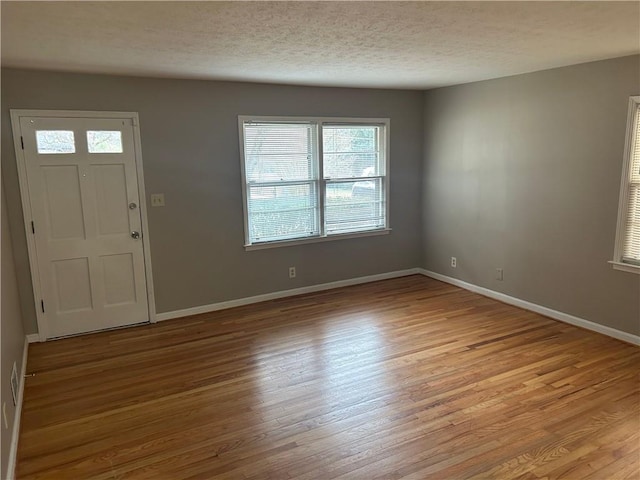 entrance foyer with baseboards, a textured ceiling, and wood finished floors