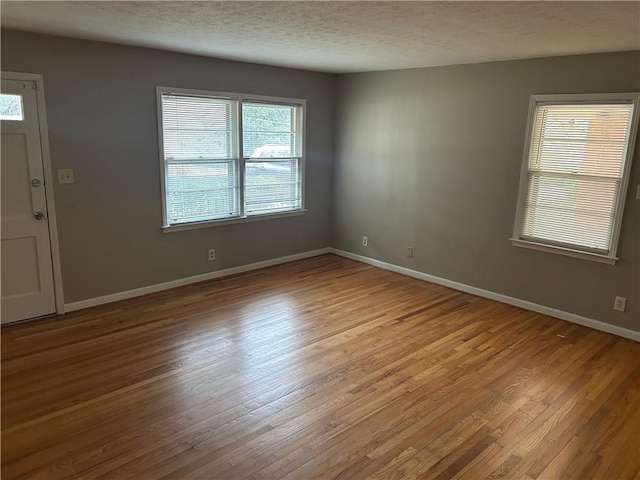 interior space with baseboards, a textured ceiling, and light wood-style floors