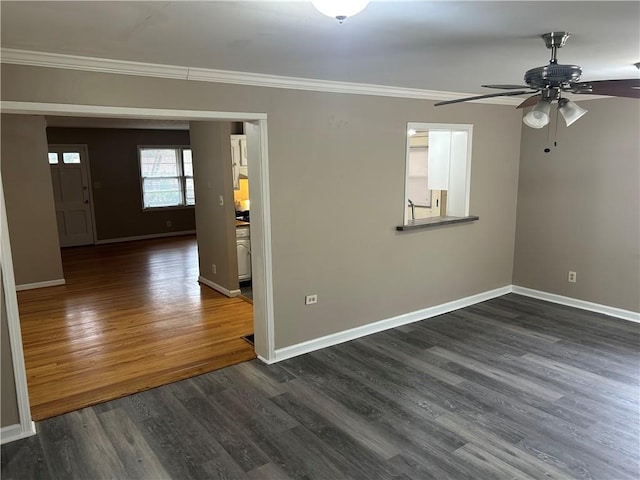 empty room featuring ornamental molding, dark wood-style floors, baseboards, and ceiling fan