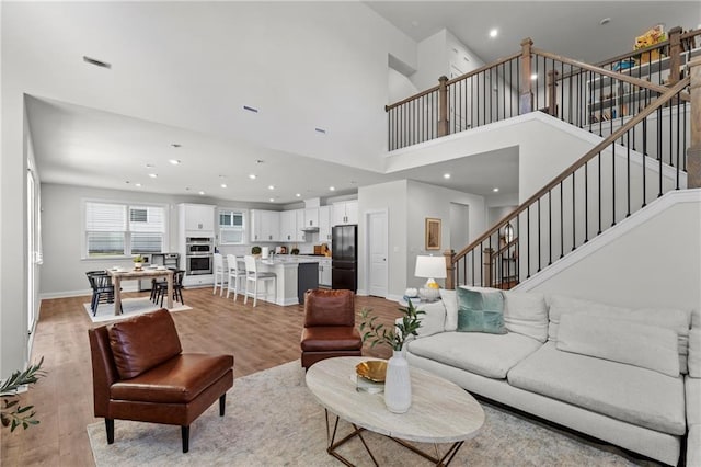 4011 Fallen Leaf Ct, Kennesaw, GA 30152 - living room featuring recessed lighting, a high ceiling, light wood-type flooring, stairs, and baseboards