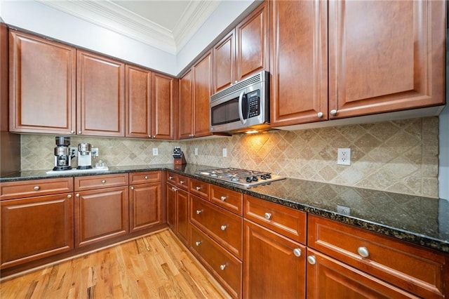 2380 Crescent Park Ct Unit 4, Atlanta, GA 30339 - kitchen featuring appliances with stainless steel finishes, crown molding, light wood finished floors, dark stone counters, and decorative backsplash