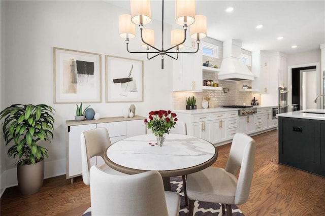 dining area featuring sink, dark wood-type flooring, and an inviting chandelier