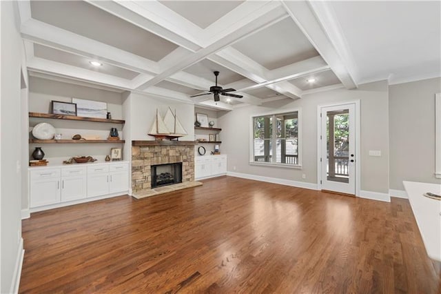 unfurnished living room with ceiling fan, beam ceiling, coffered ceiling, dark hardwood / wood-style flooring, and a stone fireplace