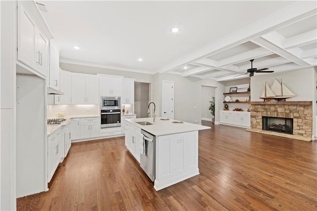 kitchen with appliances with stainless steel finishes, hardwood / wood-style floors, an island with sink, sink, and white cabinets