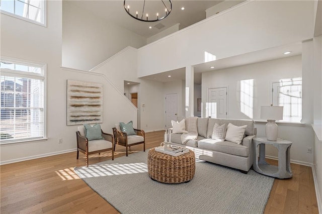 living area featuring a wealth of natural light, a notable chandelier, and light wood-style flooring