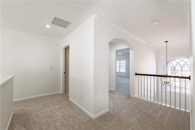 hallway featuring visible vents, baseboards, crown molding, and carpet