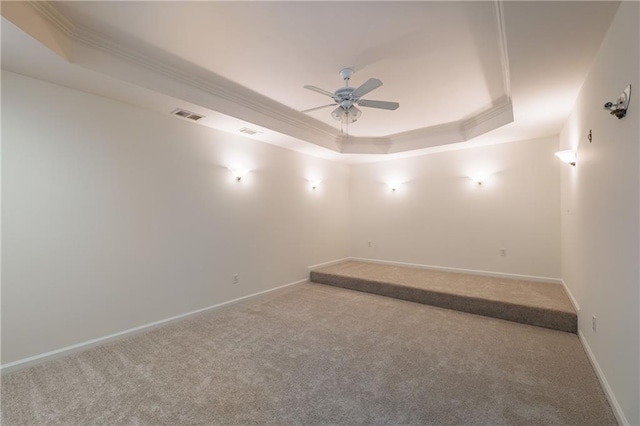 unfurnished room featuring a tray ceiling, visible vents, crown molding, and carpet flooring