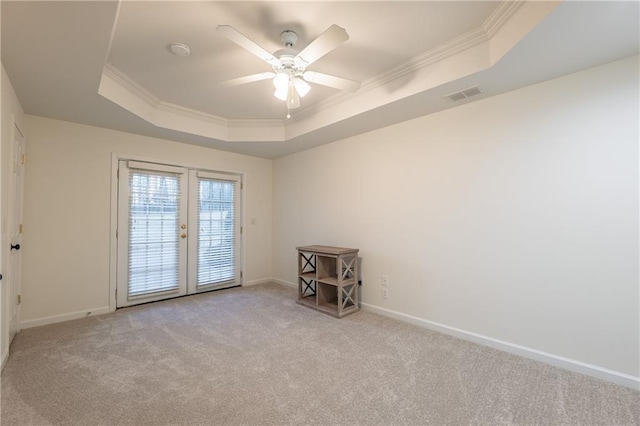 empty room featuring visible vents, carpet floors, baseboards, crown molding, and a raised ceiling