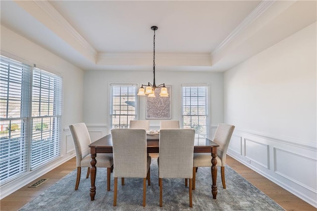 dining room with a tray ceiling, dark wood-style floors, and visible vents