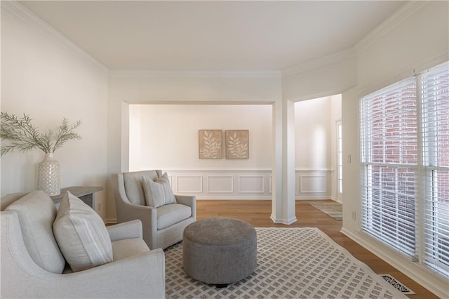 sitting room featuring a decorative wall, wood finished floors, visible vents, and ornamental molding