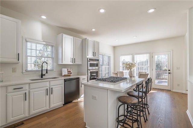 kitchen featuring a center island, a breakfast bar area, appliances with stainless steel finishes, white cabinetry, and a sink