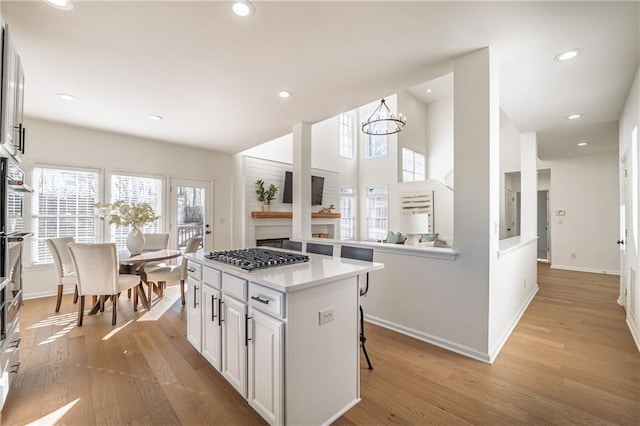 kitchen featuring a kitchen island, white cabinetry, light wood finished floors, light countertops, and stainless steel gas cooktop