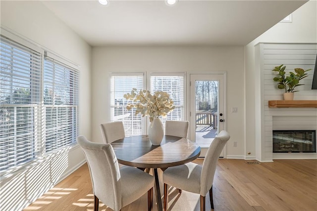 dining space featuring visible vents, baseboards, light wood-style floors, and a fireplace