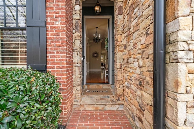 view of exterior entry featuring stone siding and brick siding