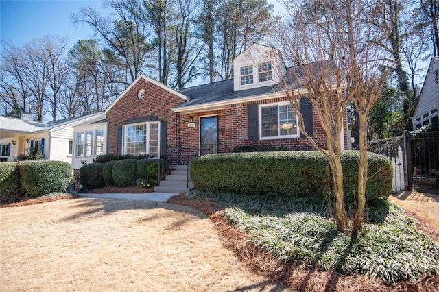 view of front of home featuring brick siding and fence