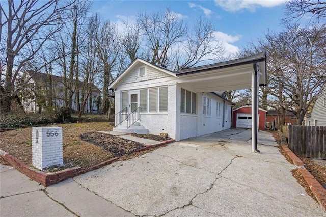 bungalow-style house with brick siding, driveway, an outdoor structure, and fence