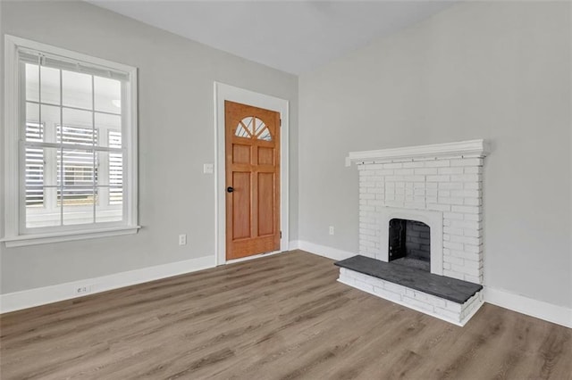 foyer featuring a brick fireplace, wood finished floors, and baseboards