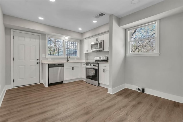 kitchen with appliances with stainless steel finishes, light wood-style flooring, visible vents, and white cabinetry