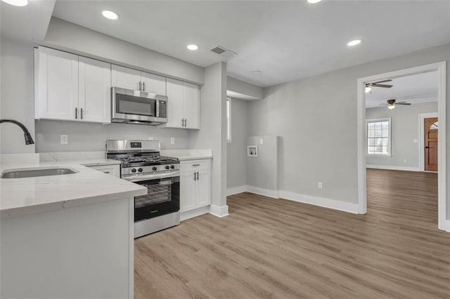 kitchen with light wood-style flooring, a sink, visible vents, white cabinetry, and appliances with stainless steel finishes