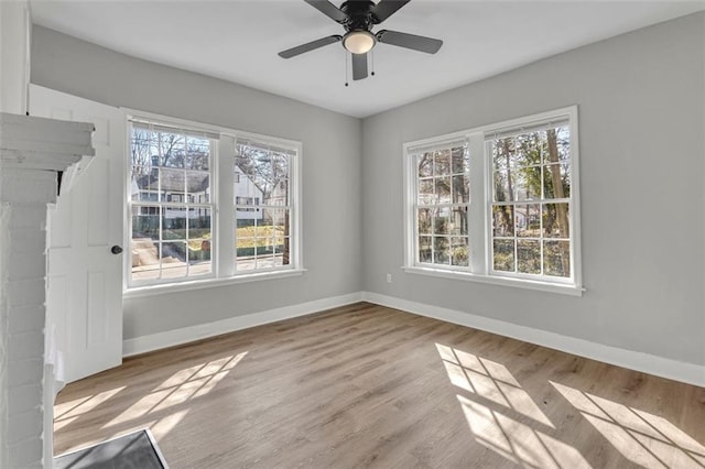 spare room featuring ceiling fan, baseboards, a wealth of natural light, and wood finished floors