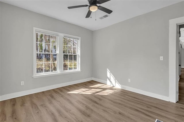 empty room featuring visible vents, ceiling fan, baseboards, and wood finished floors