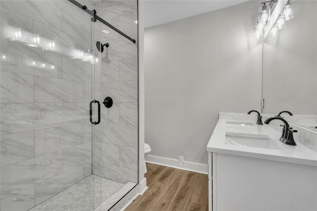 bathroom with a shower stall, wood finished floors, a sink, and baseboards