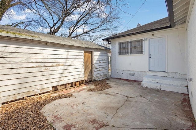 property entrance featuring crawl space, roof with shingles, and a patio