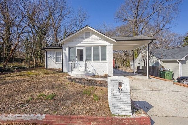 bungalow-style house featuring driveway, entry steps, a carport, and brick siding