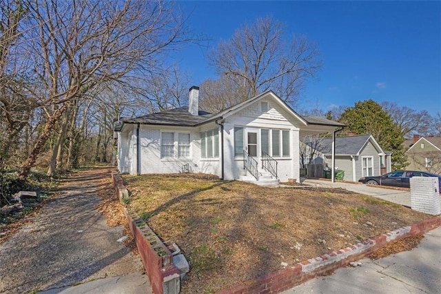 bungalow-style home featuring driveway and a chimney