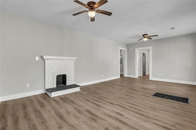 unfurnished living room featuring visible vents, a fireplace, baseboards, and wood finished floors