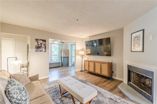 215 Cobblestone Trl, Avondale Estates, GA 30002 - living room featuring a textured ceiling, a fireplace with raised hearth, wood finished floors, ceiling fan, and baseboards