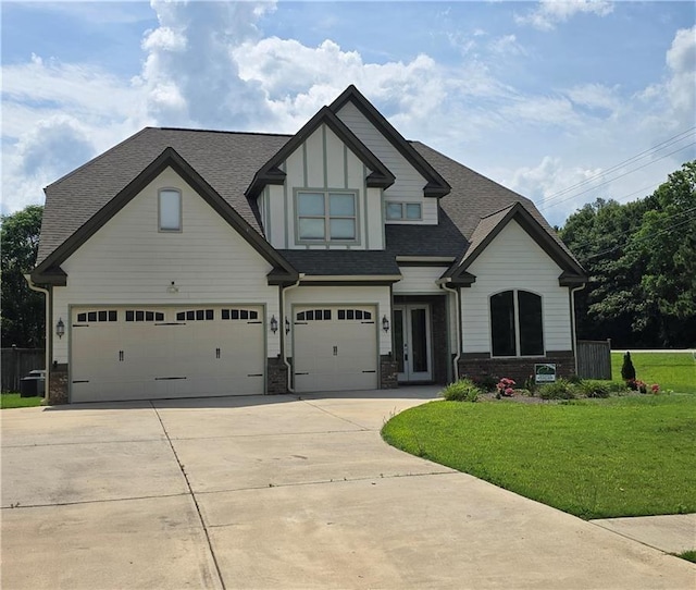 view of front of house with concrete driveway, a shingled roof, a garage, and a front lawn