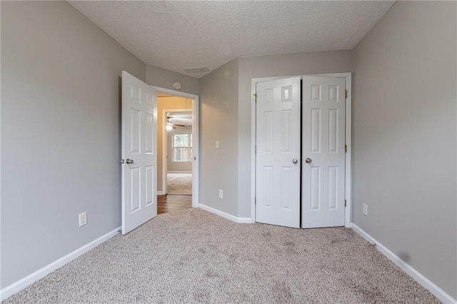 unfurnished bedroom with carpet, a textured ceiling, and a closet