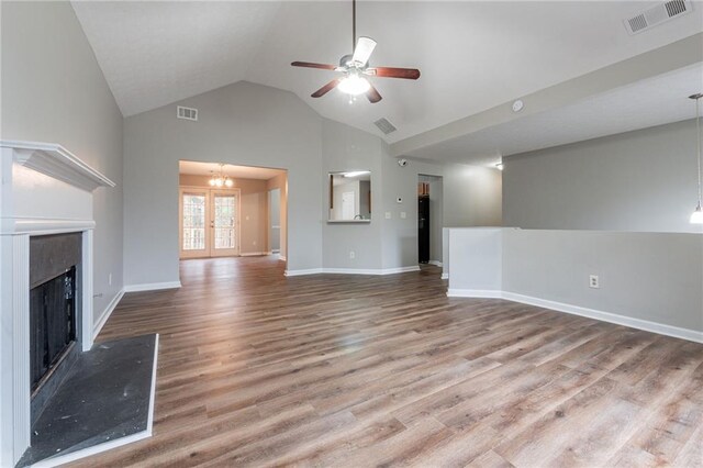 unfurnished living room featuring hardwood / wood-style flooring, ceiling fan with notable chandelier, lofted ceiling, and french doors