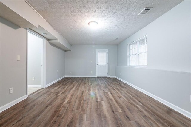 basement with a textured ceiling and dark hardwood / wood-style floors