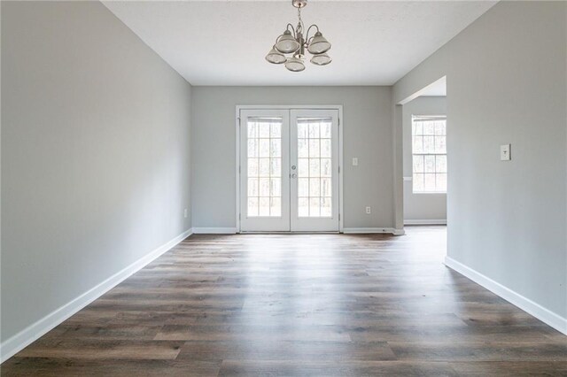 unfurnished room featuring french doors, dark wood-type flooring, and a notable chandelier