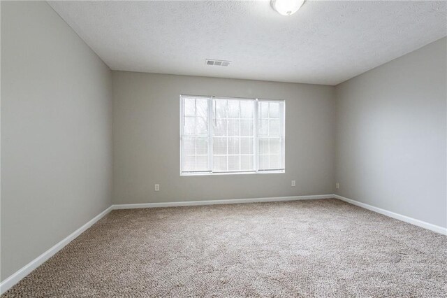 empty room with a textured ceiling and carpet floors