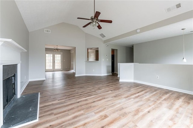 unfurnished living room with high vaulted ceiling, light hardwood / wood-style floors, and ceiling fan with notable chandelier