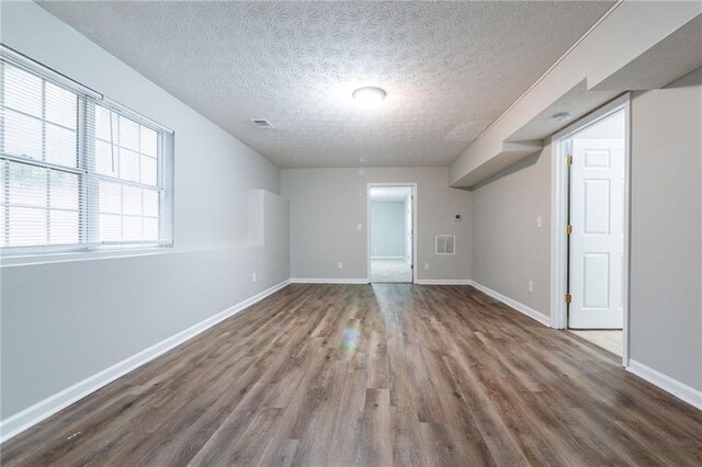 spare room featuring wood-type flooring and a textured ceiling