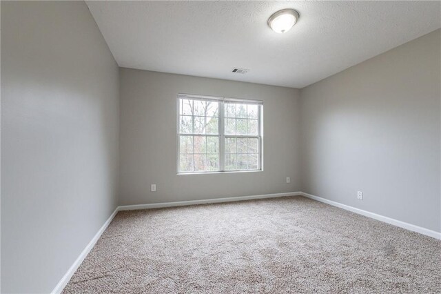 carpeted empty room featuring a textured ceiling