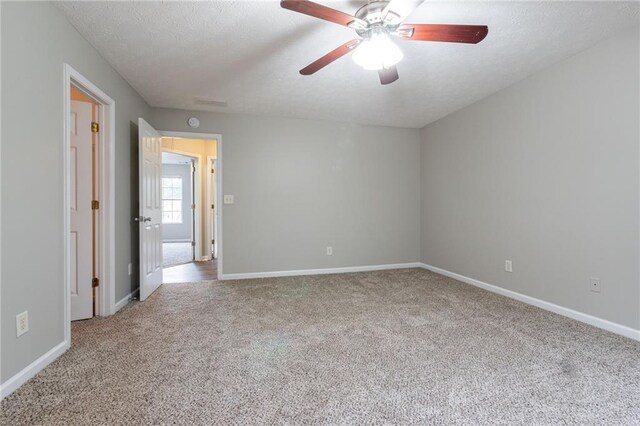 carpeted empty room with ceiling fan and a textured ceiling